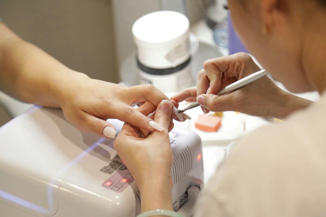Nail technician carefully shaping a client's nails